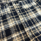 Close-up of navy-and-cream plaid fabric with small round decorative buttons