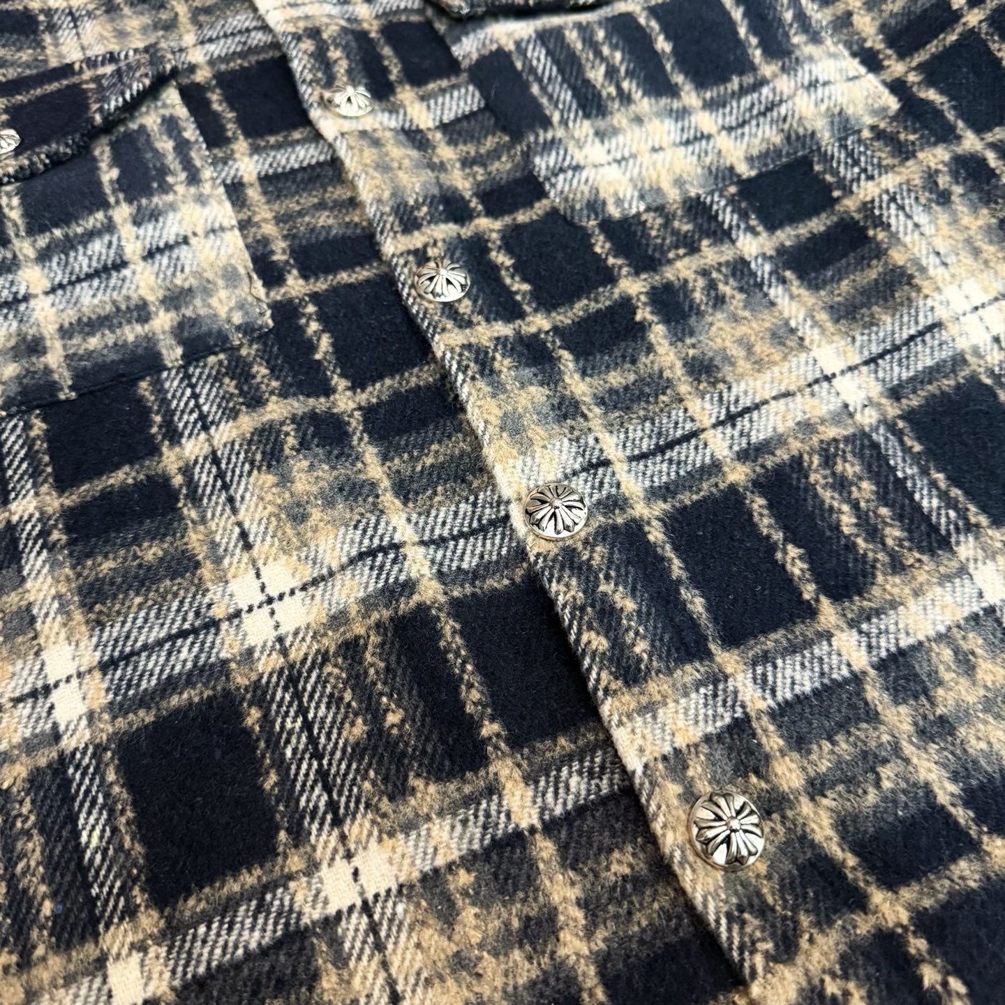 Close-up of navy-and-cream plaid fabric with small round decorative buttons