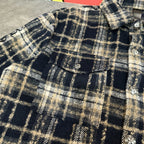 Close-up of navy-and-cream plaid long-sleeve shirt with decorative metal buttons
