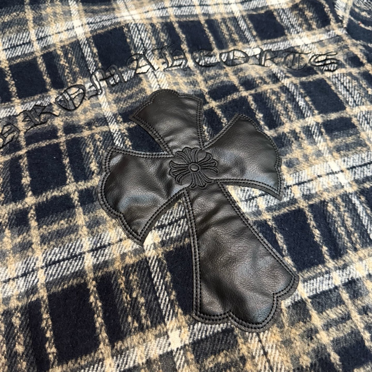 Cross applique detail on long plaid shirt with stitched decorative border