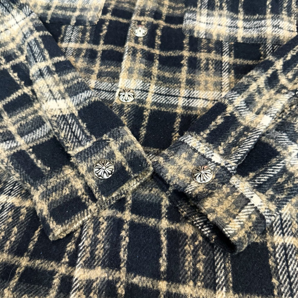 Close-up of navy-and-cream plaid long-sleeve shirt with decorative buttons near seams