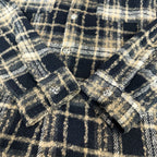 Close-up of navy-and-cream plaid long-sleeve shirt with decorative buttons near seams