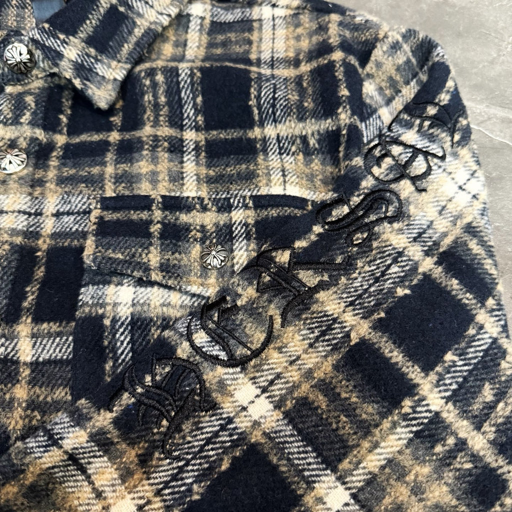 Close-up of navy-and-cream plaid sleeve with bow-like trim and decorative buttons
