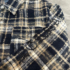Close-up of navy-and-cream plaid sleeve with bow-like trim and decorative buttons