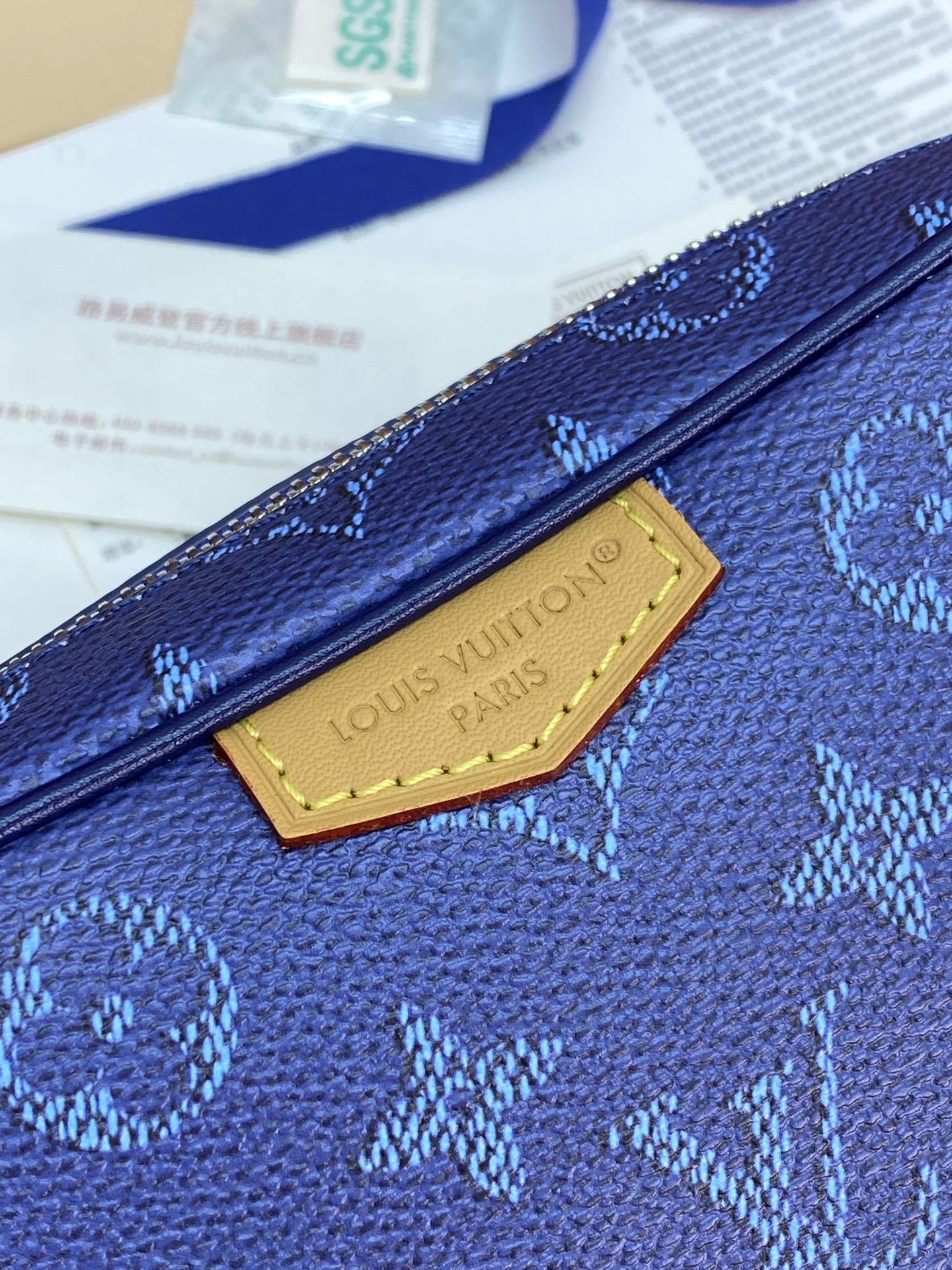 Blue monogram crossbody bag with gold-toned logo plaque on front