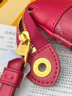 Pink leather zip wristlet with gold zipper pull, Louis Vuitton logo medallion, and stitching detail