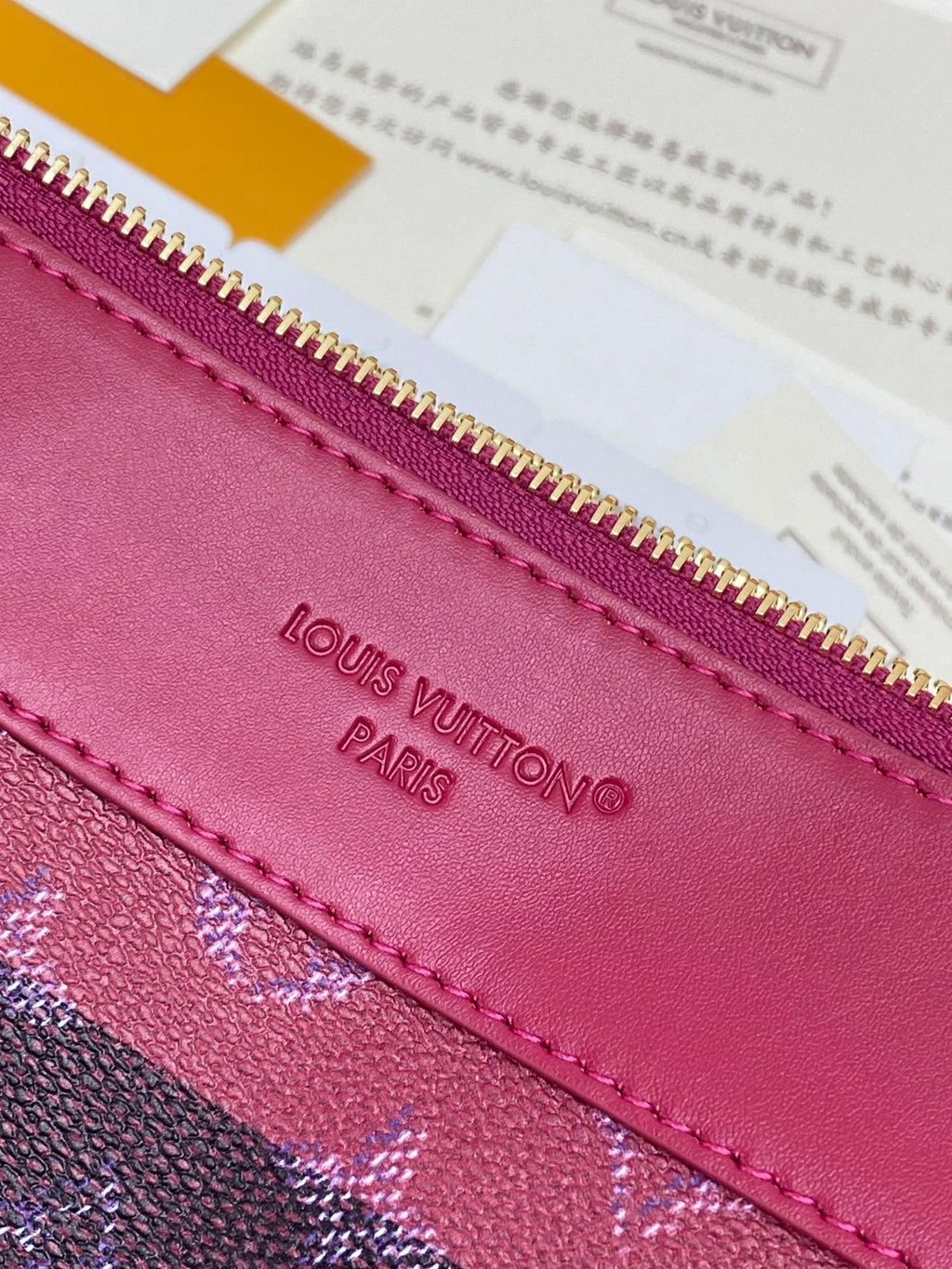 Louis Vuitton Paris embossed on magenta leather trim near gold zipper