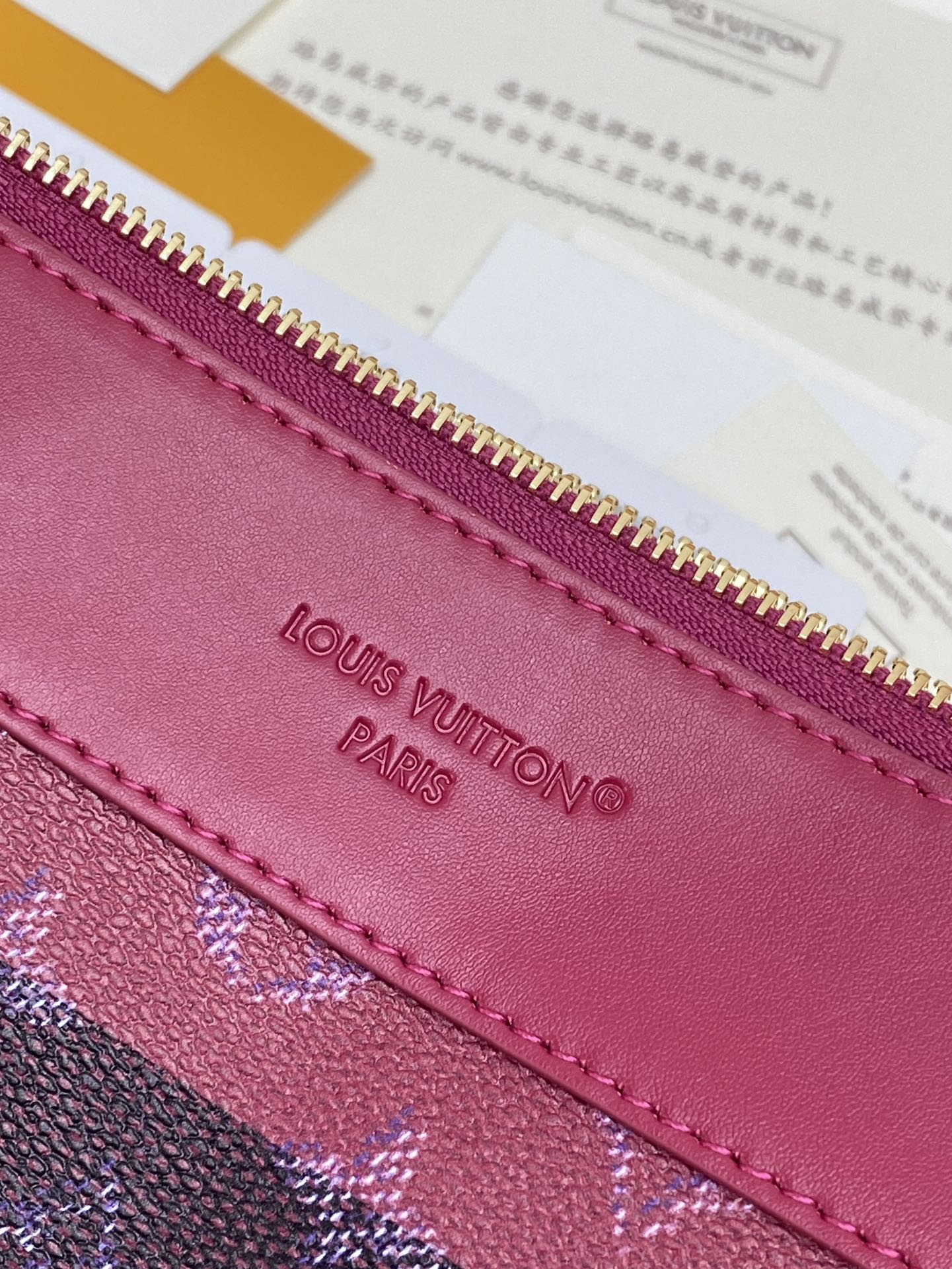 Louis Vuitton Paris embossed on magenta leather trim near gold zipper