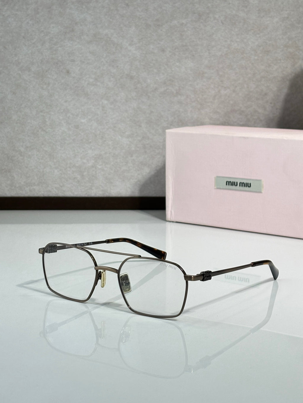 MiuMiu sunglasses, dark frame with gold details and clear temple arms