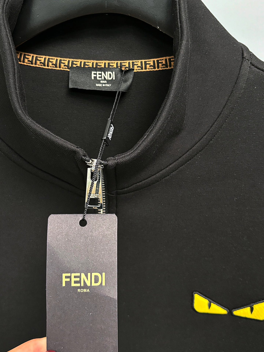 Fendi black zip-up sweatshirt neck label with dangling tag and yellow logo