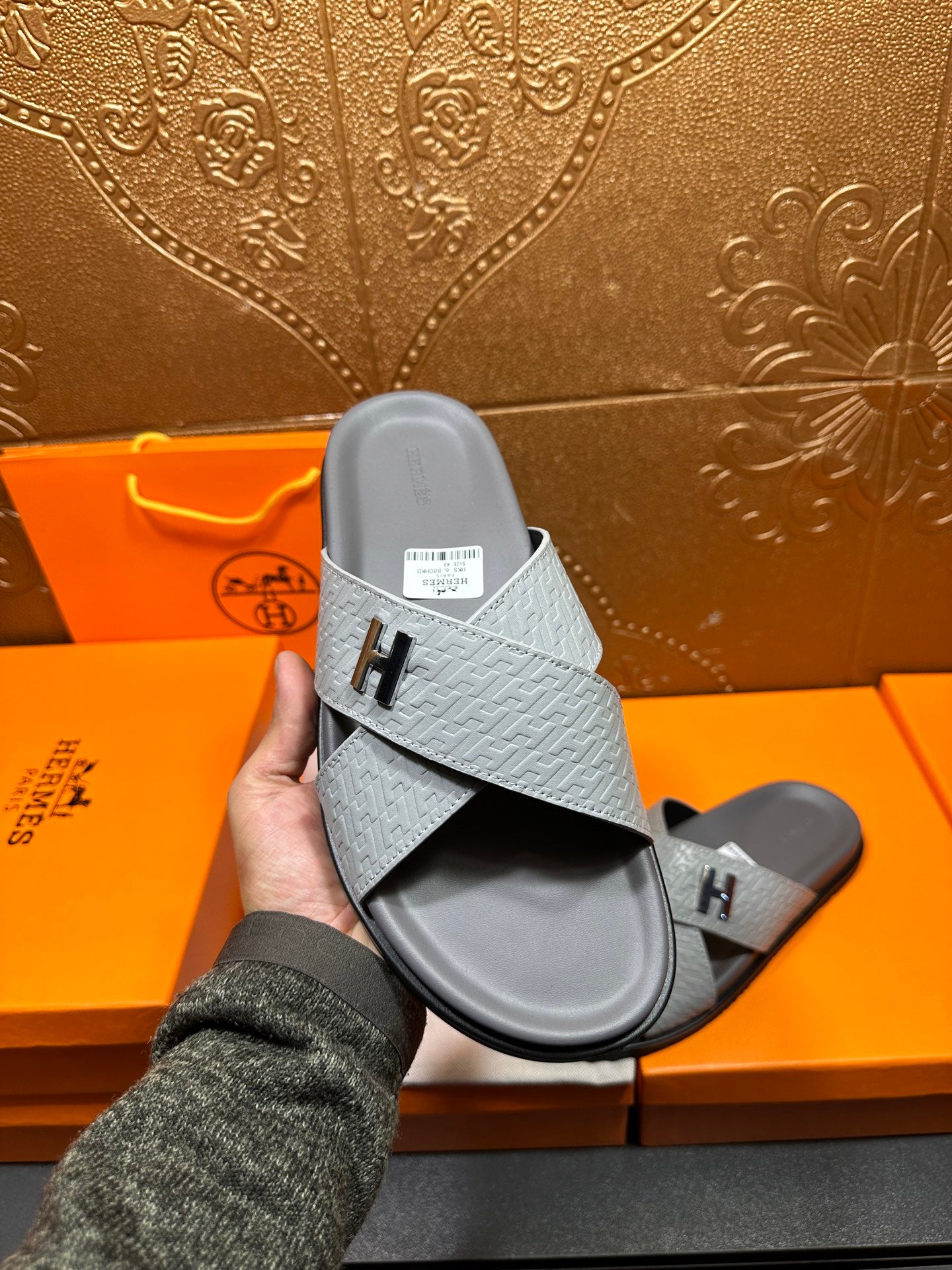 Hermes slide sandals held up, light blue cross-strap with H logo and dark sole