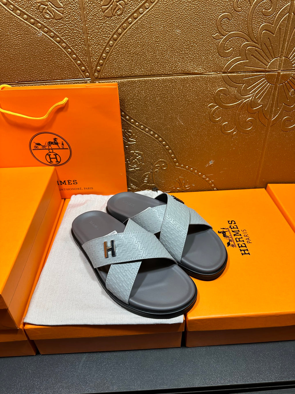 Hermes slide sandals on white cloth, light blue straps with stitched H logo