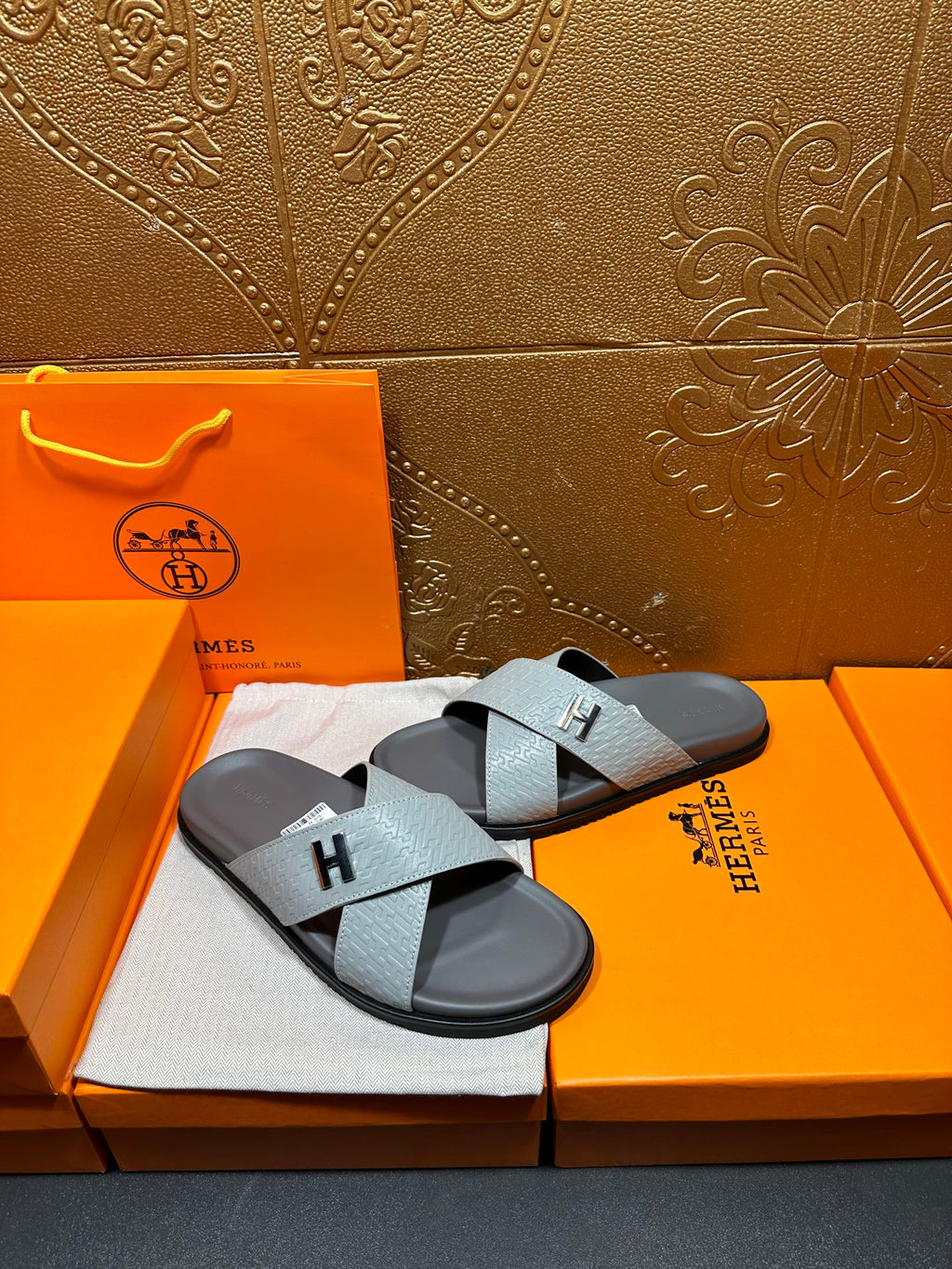 Hermes slide sandals with light blue straps and black H buckle on dark soles