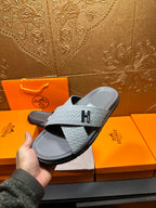 Hermes slide sandals held in hand, light blue embossed straps and dark rubber sole
