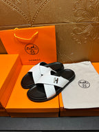 Pair of white-and-black H logo slide sandals with wide crisscross strap