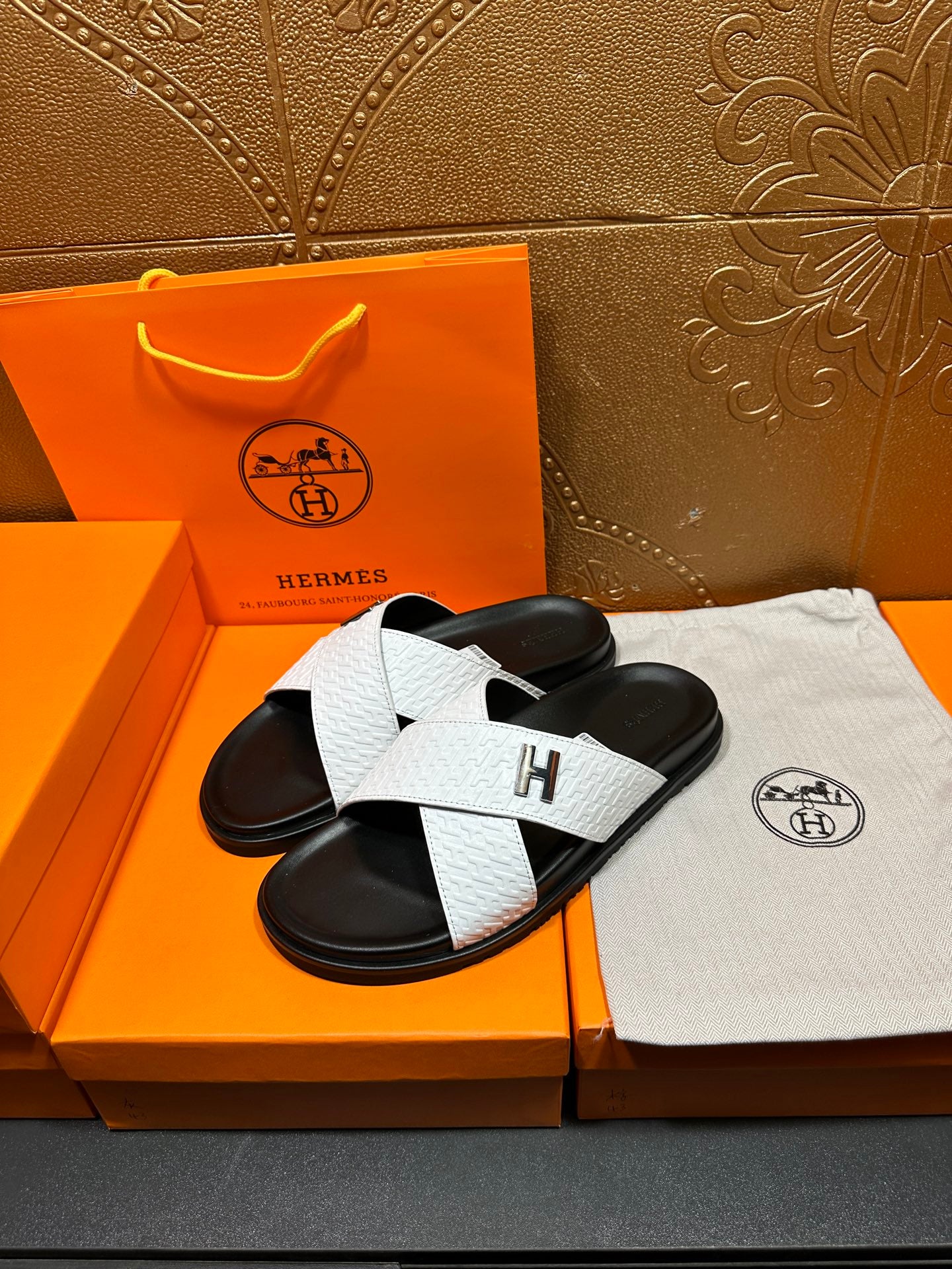 Pair of white-and-black H logo slide sandals with wide crisscross strap