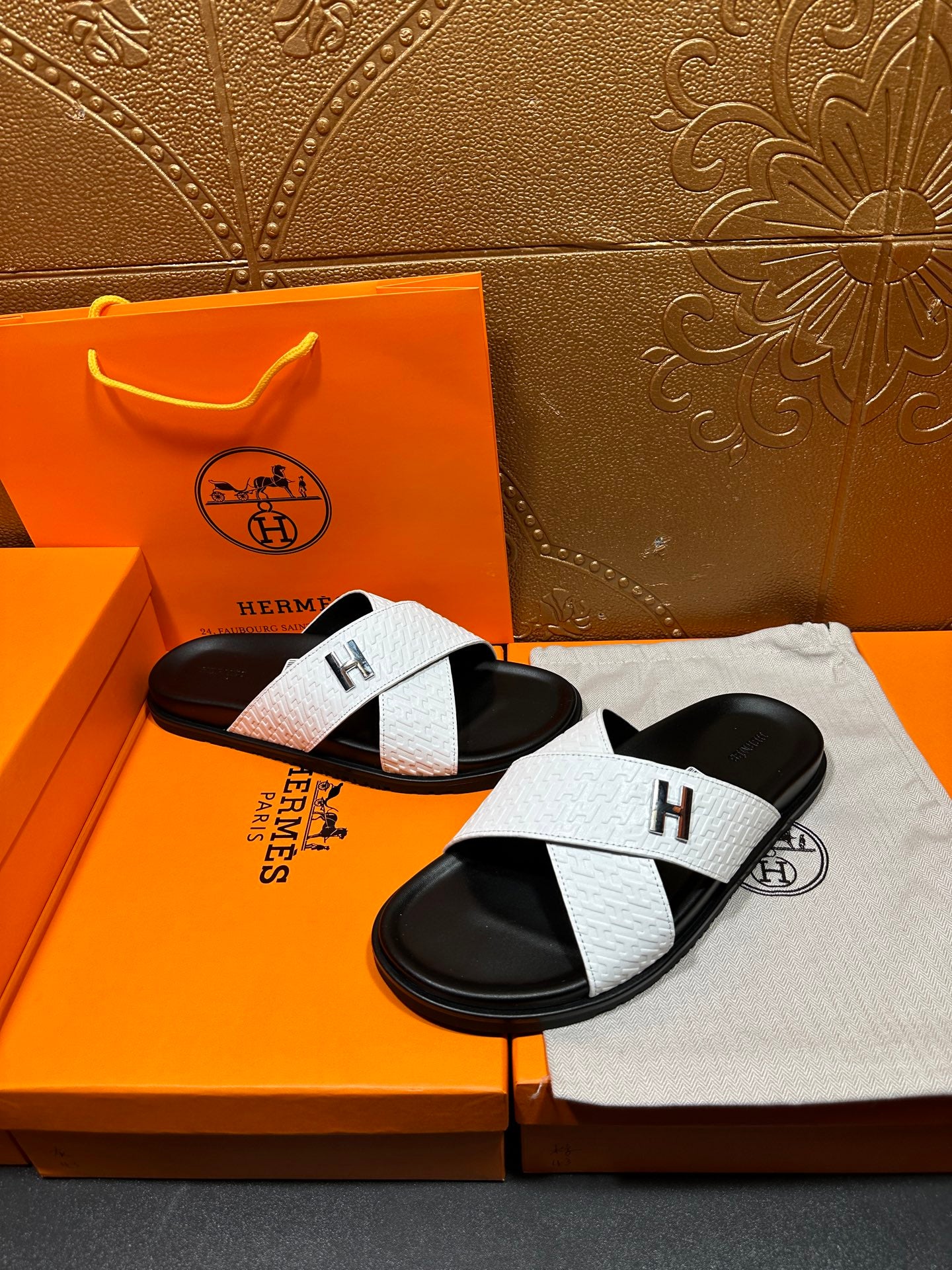 White textured H logo slide sandals on black footbeds, shown with both shoes
