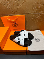 White crisscross-strap slide sandals with black sole and H emblem on the strap