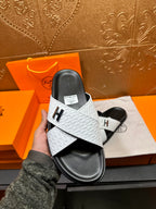 Hand-held white slide sandal with black sole and H emblem on the cross strap
