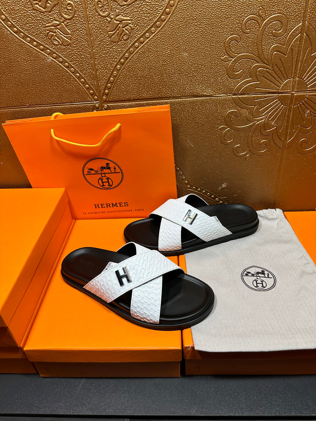 White and black H logo slide sandals with textured strap and open toe