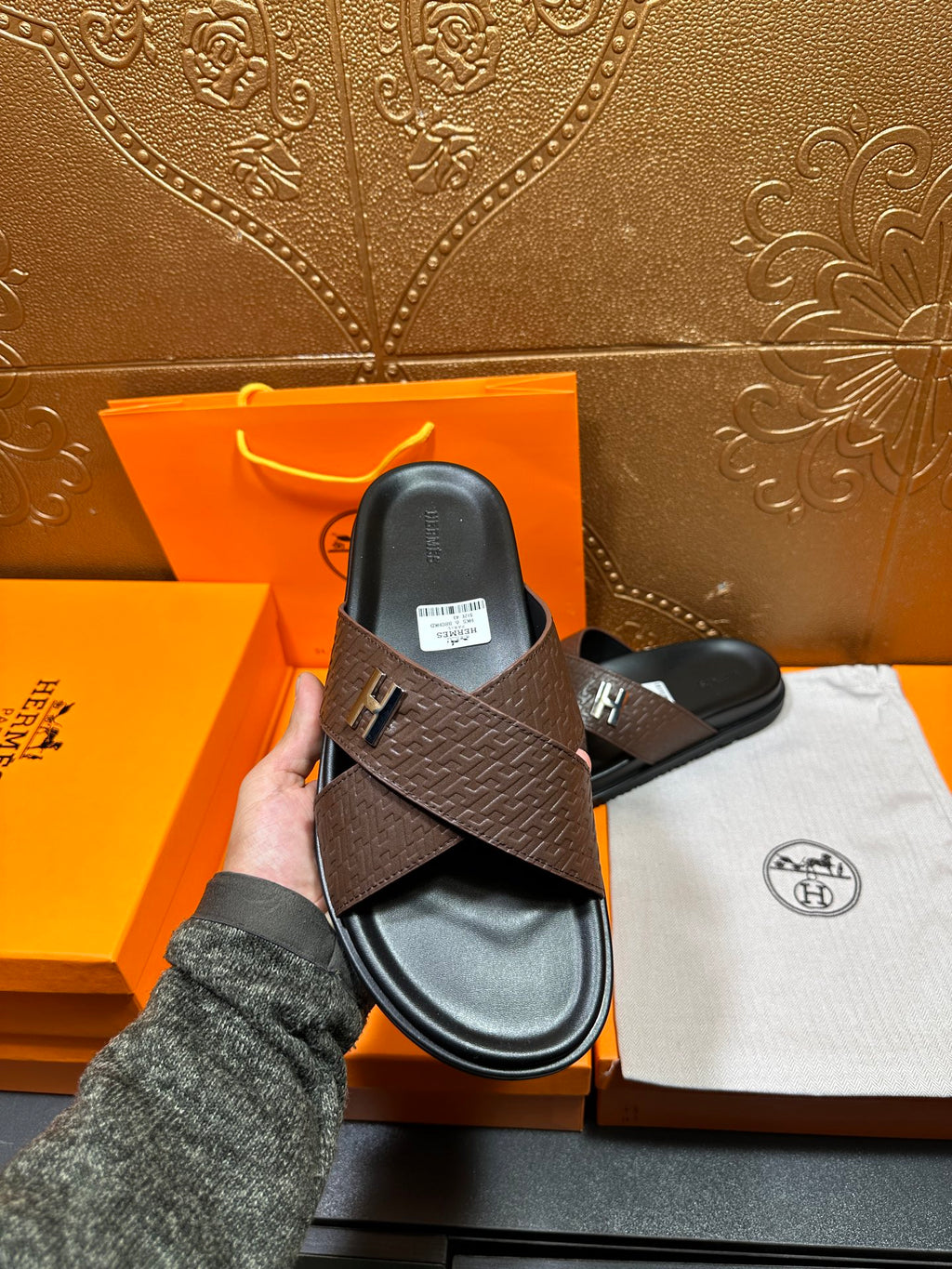 Brown textured leather slide sandals, black footbed, H buckle; held upright