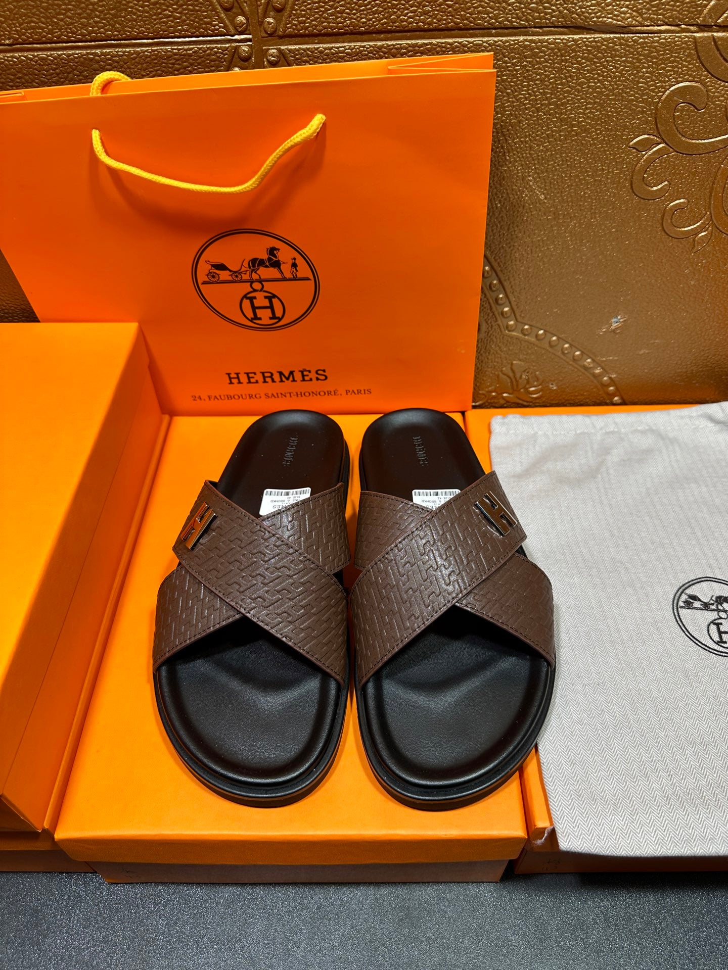 Brown textured leather slide sandals with black footbed and H buckle