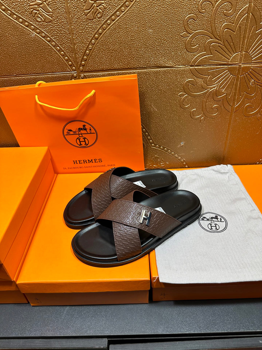 Brown leather slide sandals with black footbed and H-shaped front buckle