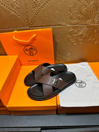 Brown leather slide sandals with black footbed and H-shaped front buckle