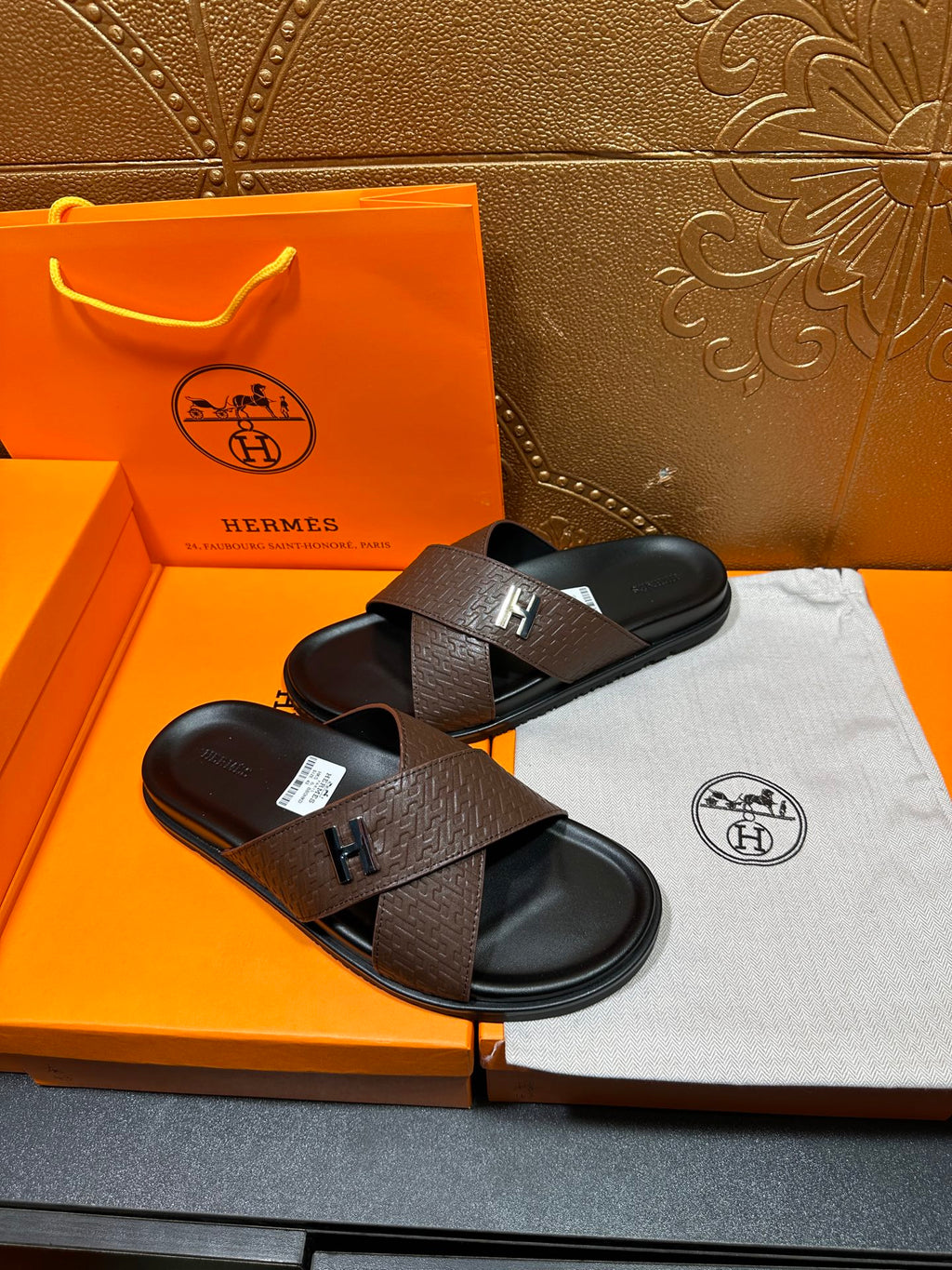 Brown leather slide sandals with black footbed and H buckle strap