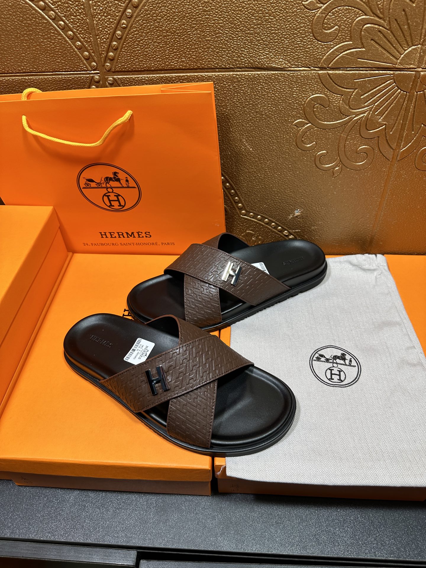 Brown leather slide sandals with black footbed and H buckle strap