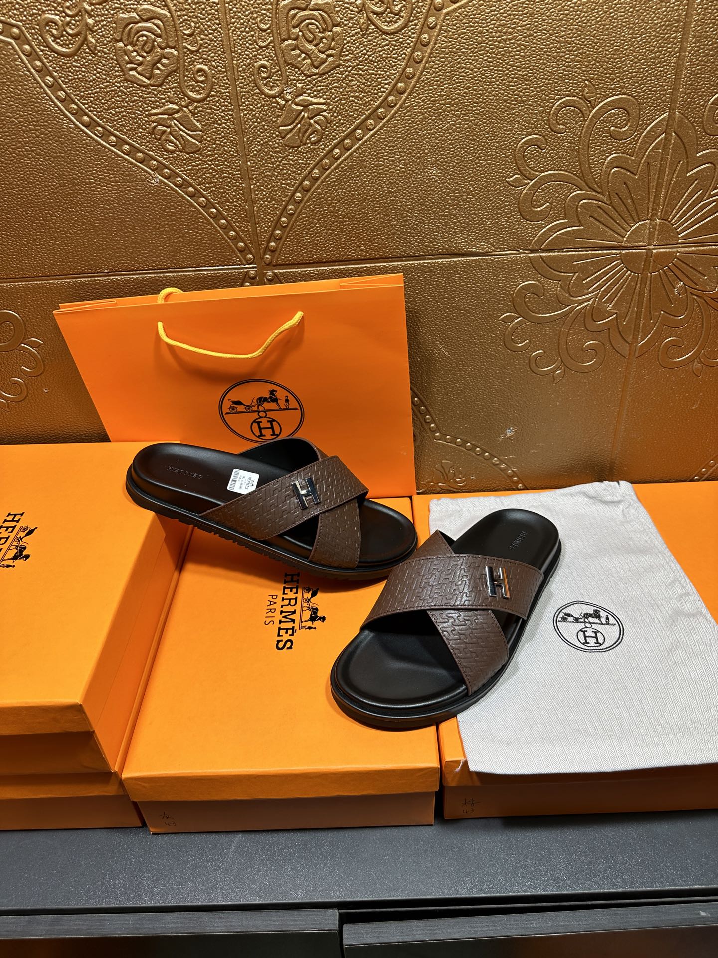 Brown textured leather slide sandals with black footbed and H buckle, side view