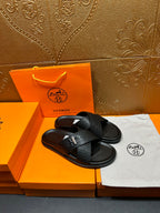 Black leather slide sandals with H buckle and textured upper, flat sole