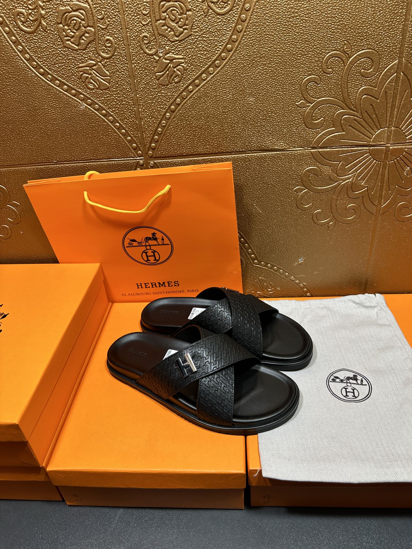 Black leather slide sandals with H buckle and textured upper, flat sole