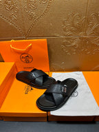 Black textured slide sandals with H buckle and cushioned footbed, flat sole