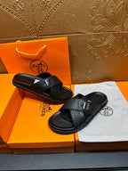 Pair of black textured slide sandals with H buckle and flat sole