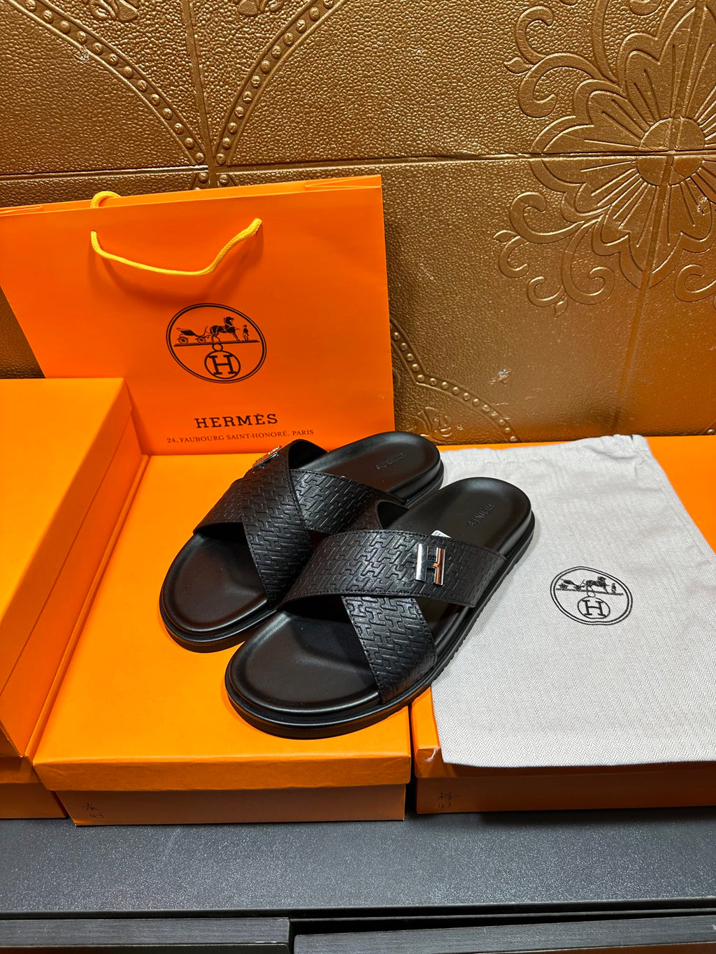 Black textured slide sandals with single strap crossing and H buckle