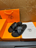Black textured slide sandals with single strap crossing and H buckle
