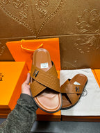 Hermes slide sandal held in hand, tan textured H-strap slide, open-toe