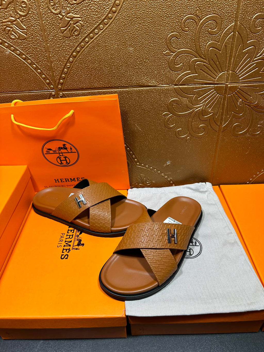 Hermes slide sandals with tan textured cross straps and H buckle, open-toe slides