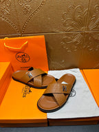 Hermes slide sandals with tan textured cross straps and H buckle, open-toe slides
