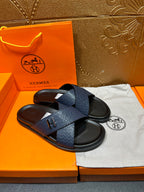 Blue slide sandals with H logo strap detail and black footbed, pair on display