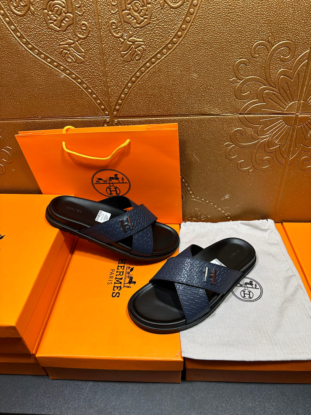 Blue slide sandals with H logo strap and textured pattern, black footbed, pair