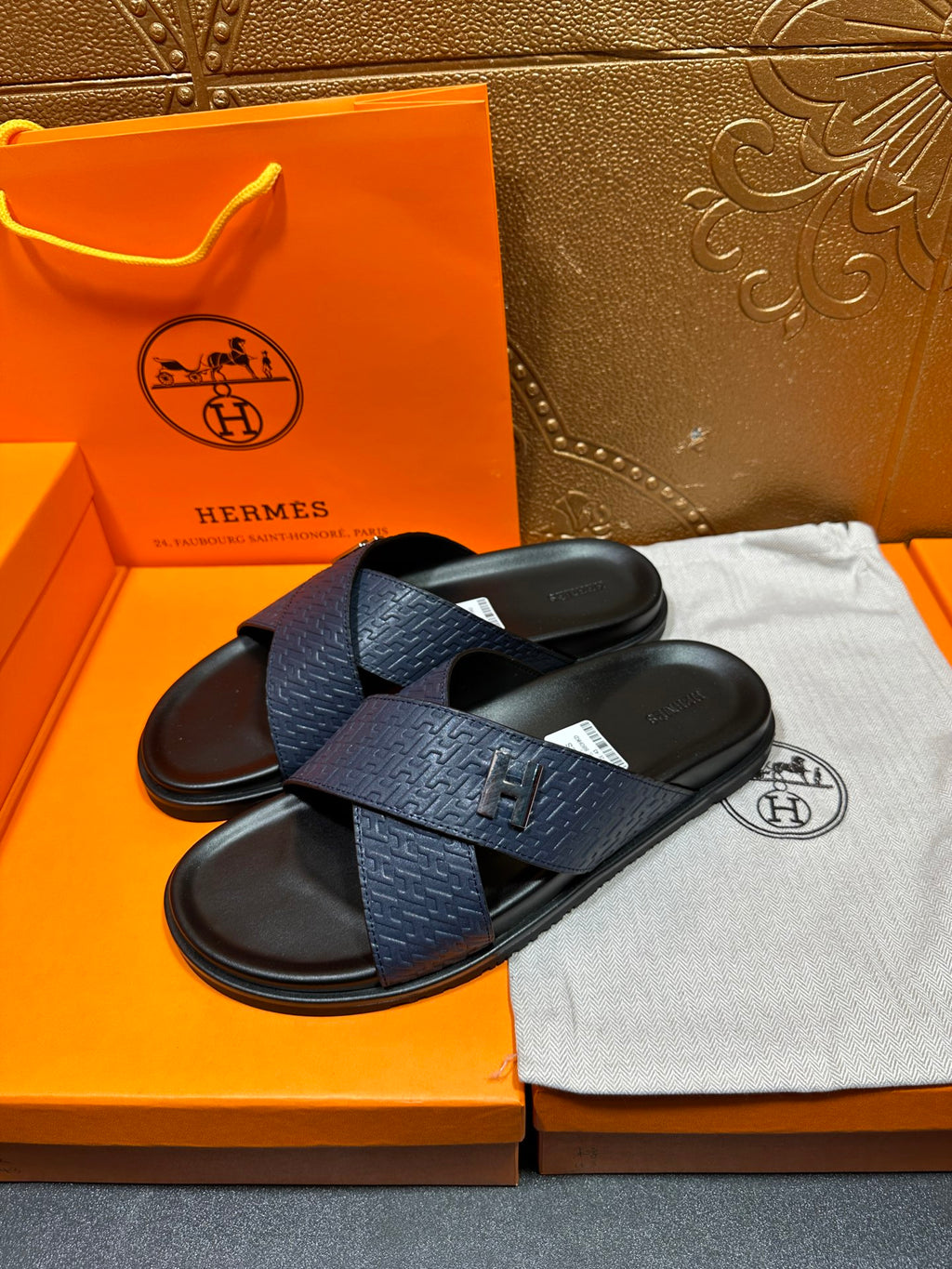 Blue slide sandals with textured H logo strap, black footbed and open toe, pair