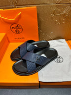Blue slide sandals with textured H logo strap, black footbed and open toe, pair