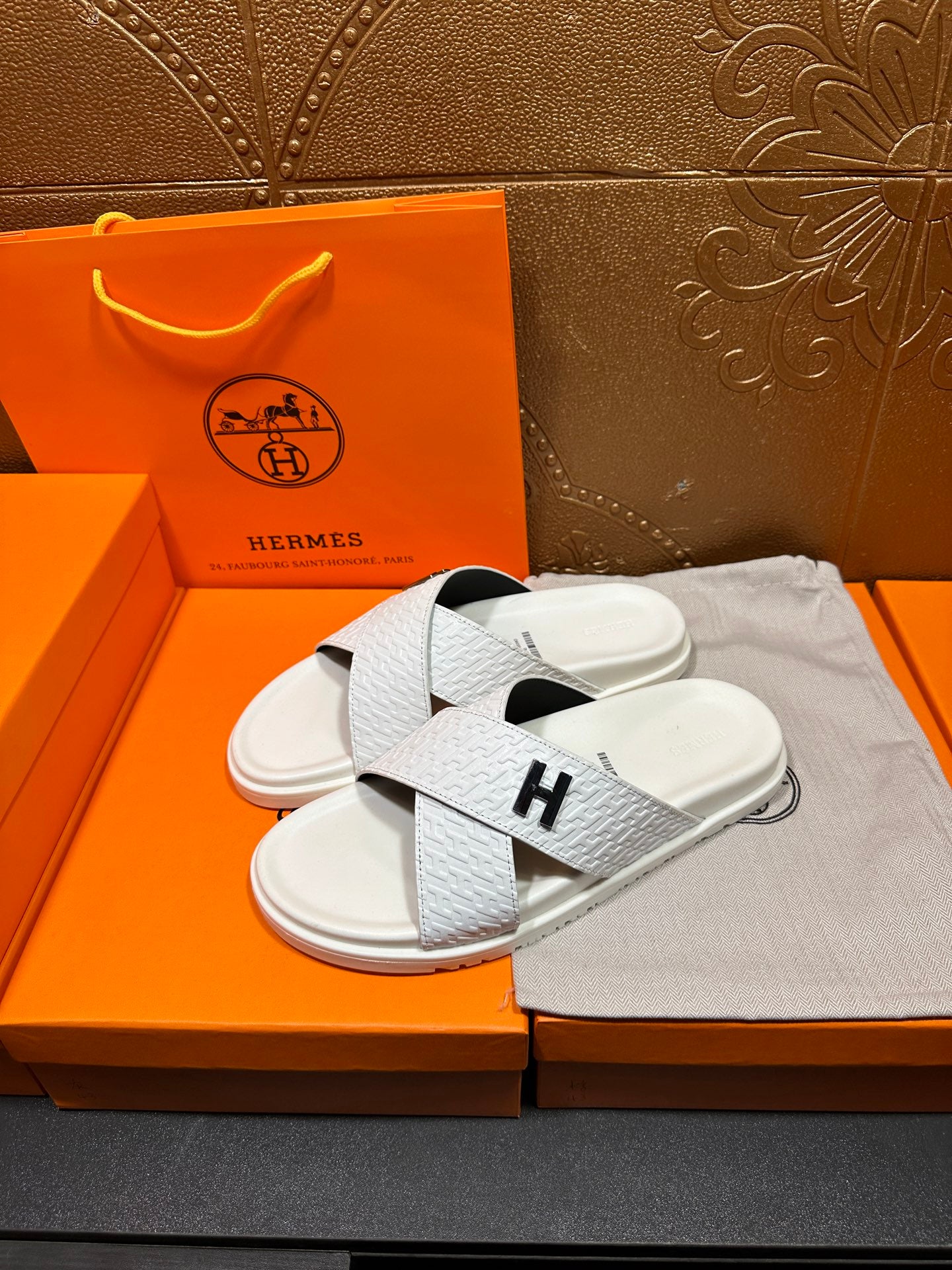 Hermes white slide sandals with textured straps and black H logo on footbed