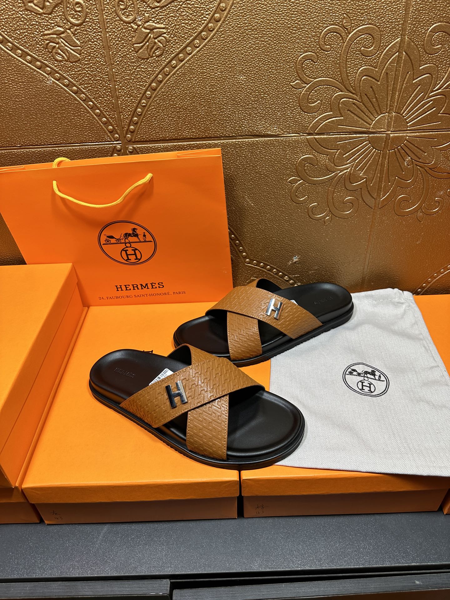 Brown textured leather slide sandals with black footbeds and stitched H strap