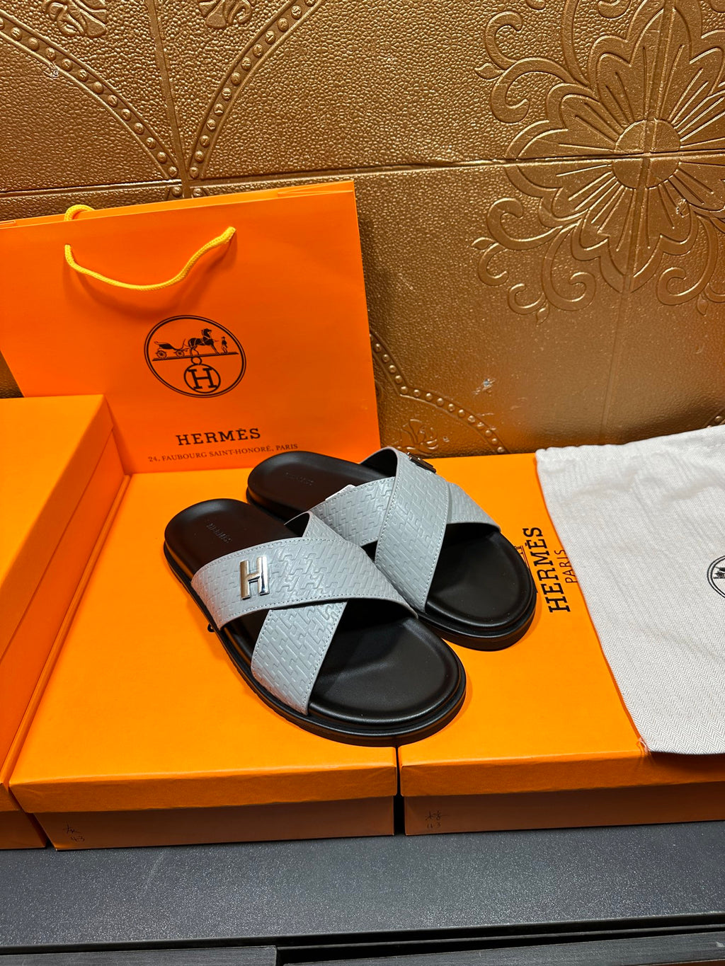 Hermes slide sandals in light gray with black footbed and H strap detail