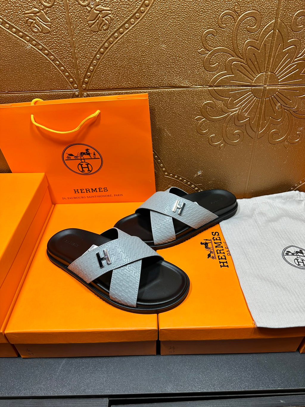 Hermes sandals with light gray textured straps and black footbed, H buckle front view