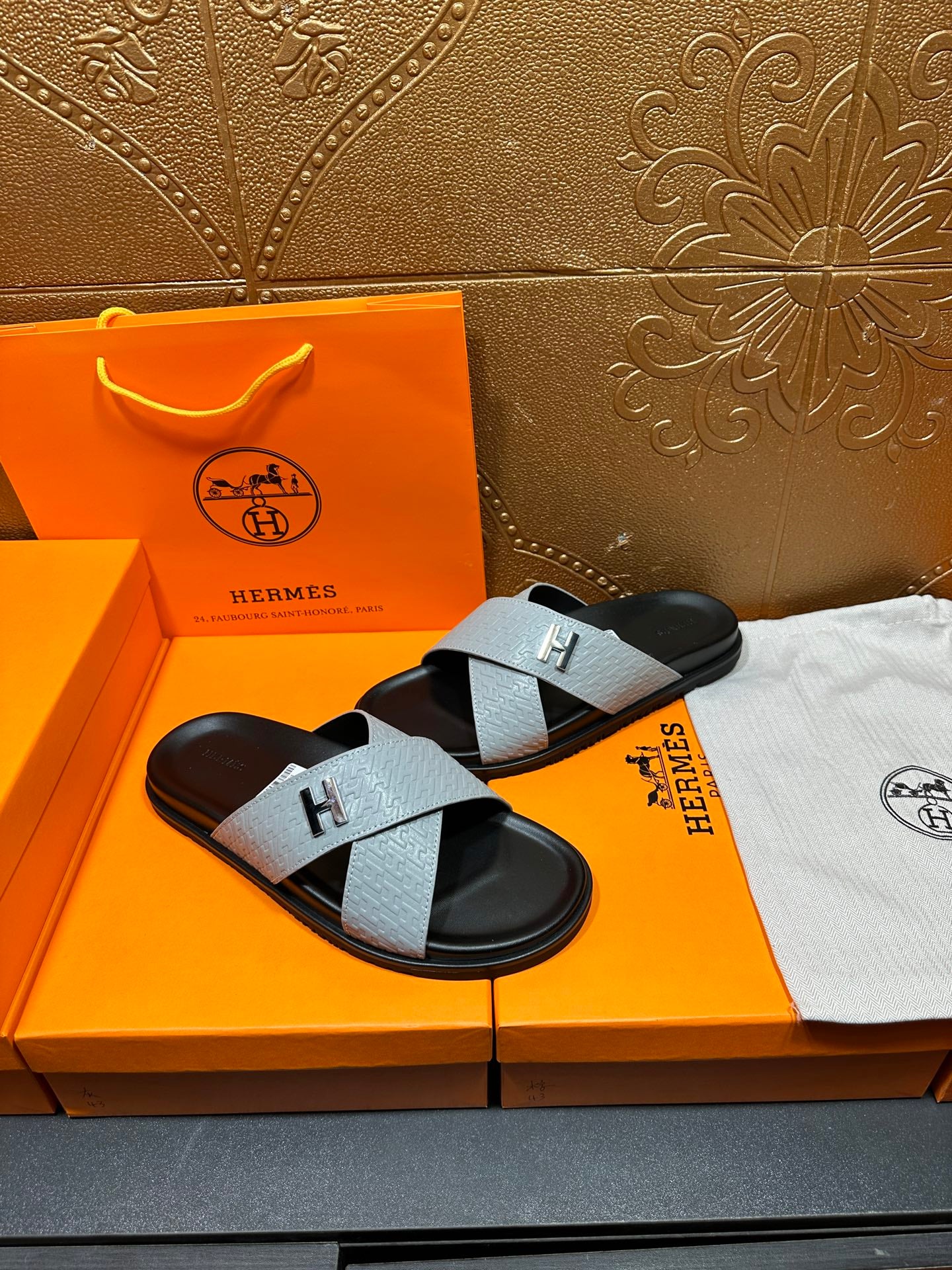 Hermes sandals with light gray textured straps and black footbed, H buckle front view