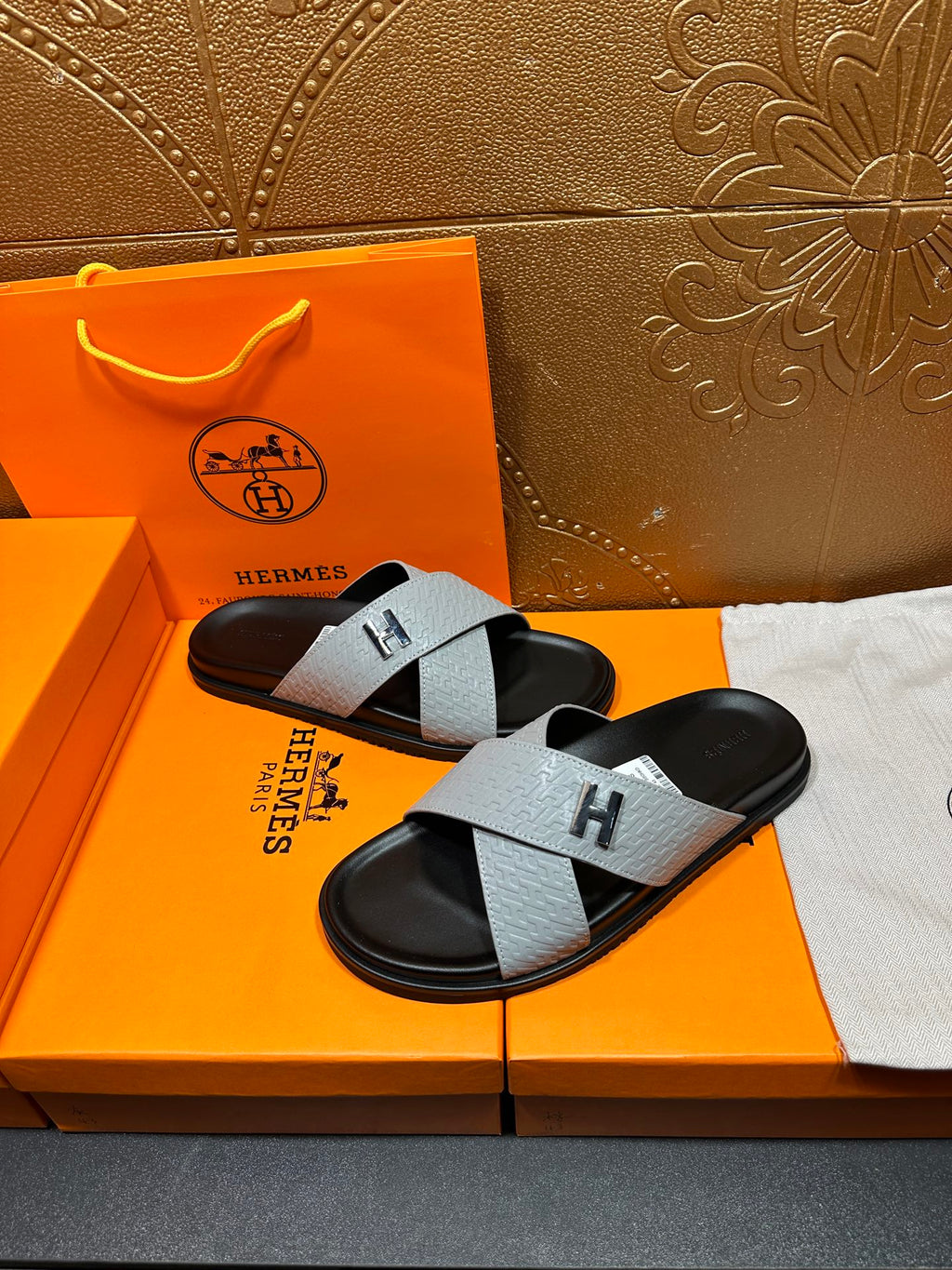 Hermes slide sandals with light gray cross straps, black footbed, H logo buckle